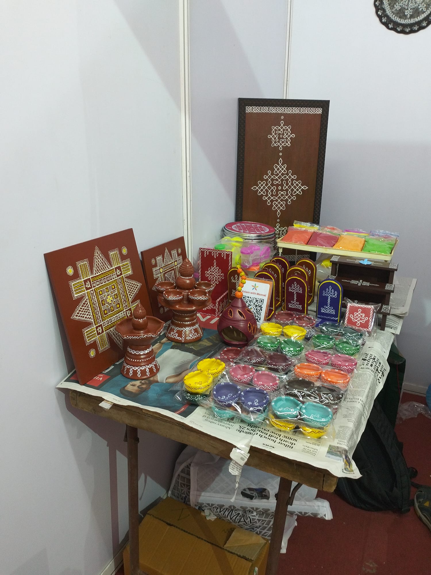 Hand-painted kolam boards, kuthuvilakku and clay diyas on the stall table